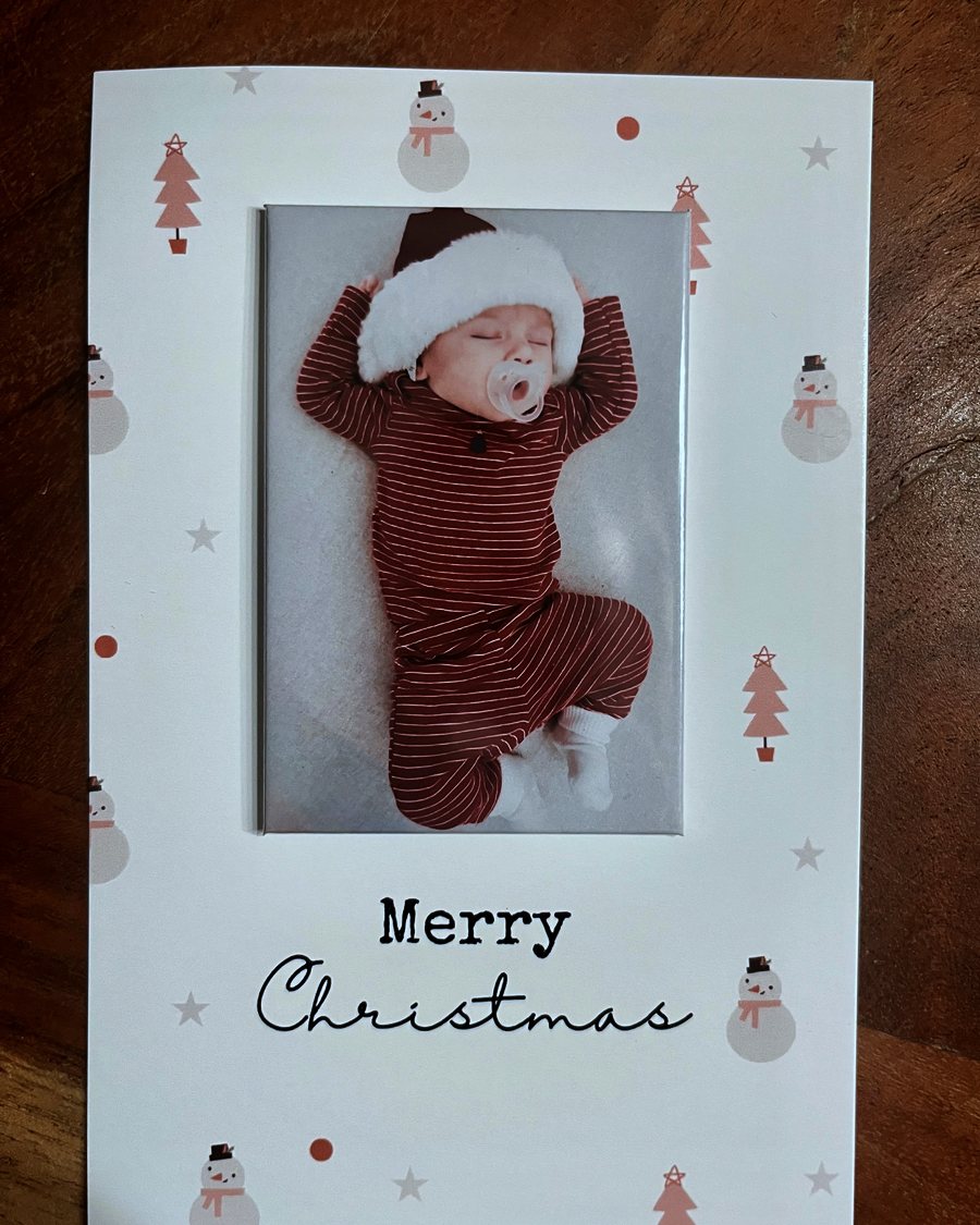 A Merry Christmas keepsake card with a removable photo magnet of a sleeping baby in a Santa hat